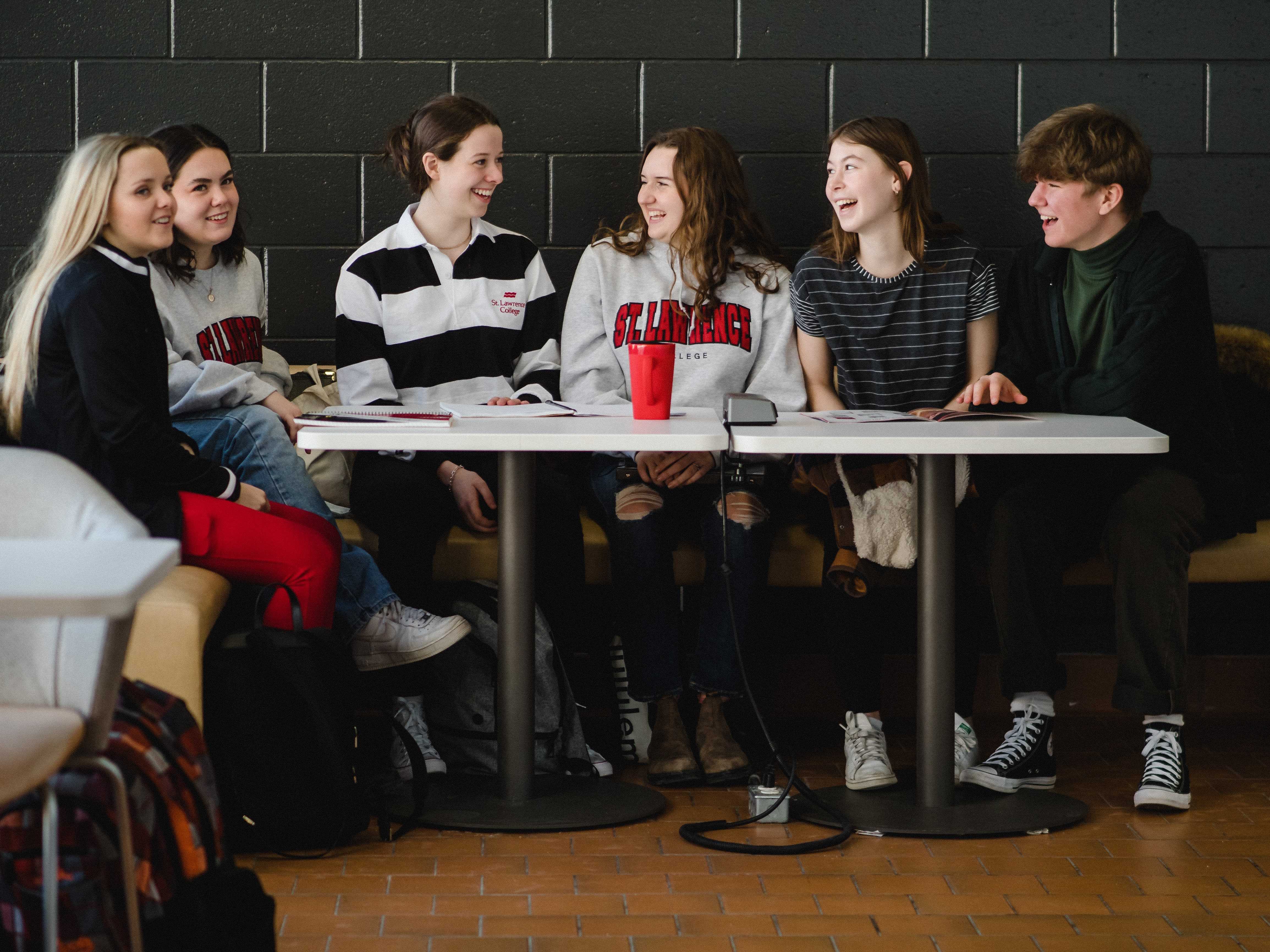 Group of students sitting at a table laughing and smiling